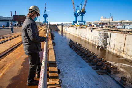 Code 982 Utilities Engineer Zechariah Nachazel observes the flooding of Dry Dock 8. Nachazel installs temporary services once the U.S. Navy vessel is docked.