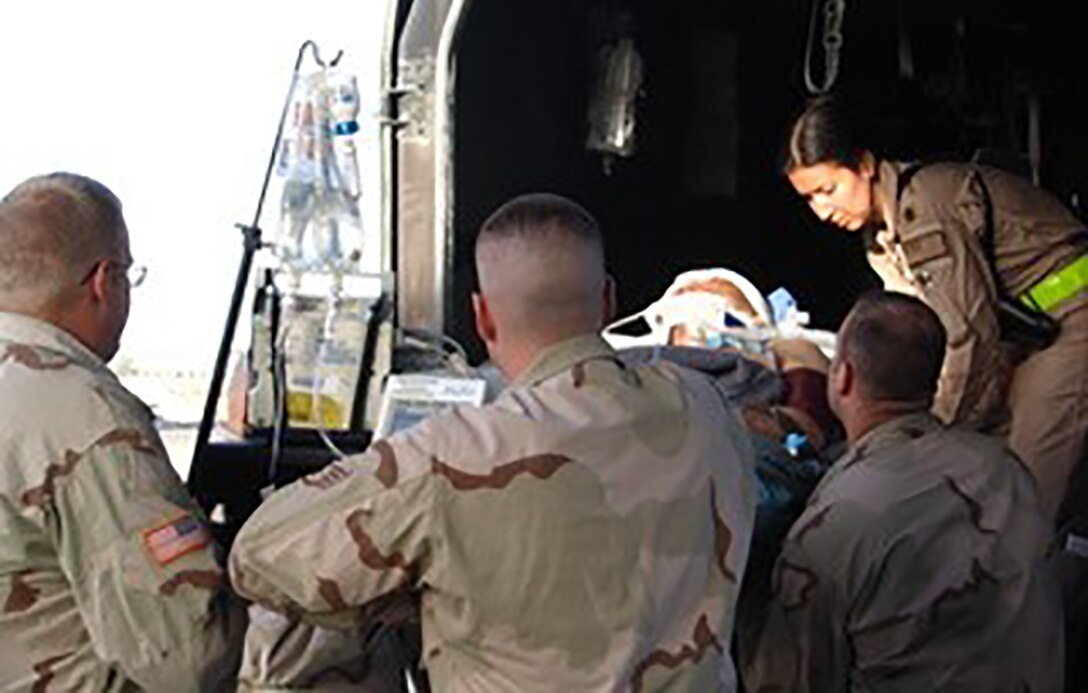 Then Lt. Col. Maria Angles, leading a Critical Care Air Transport Team, helps load a critically injured member in Kandahar, Iraq, in 2005