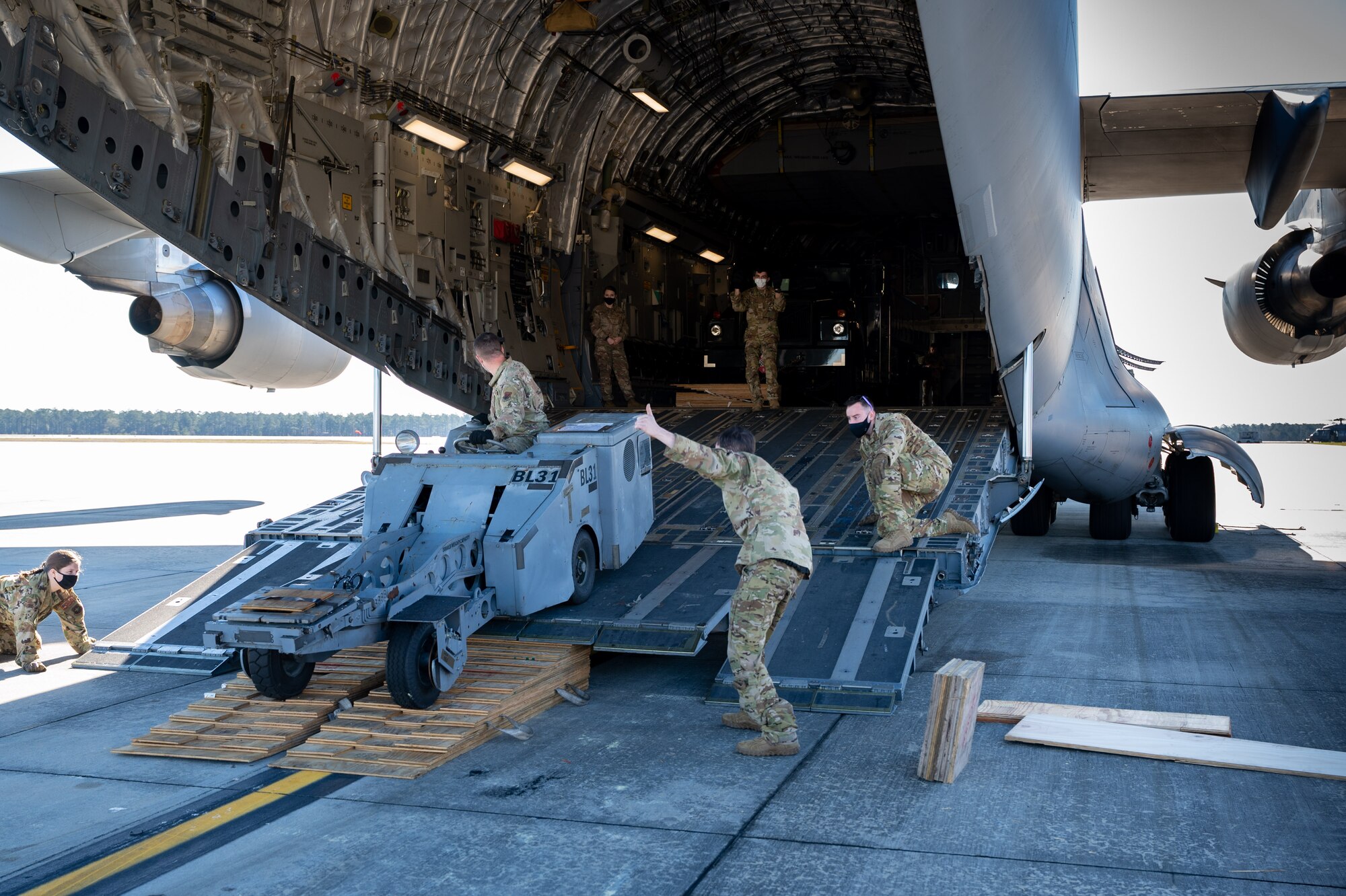 Airmen from Dover Air Force Base marshal a bomb loading cart onto a Dover AFB C-17 Globemaster III during exercise Mosaic Tiger at Moody AFB, Georgia, Feb. 23, 2021. Mobility Airmen from Dover AFB and Joint Base McGuire-Dix Lakehurst, New Jersey, participated in the exercise to enhance readiness and reinforce Air Mobility Command support to the joint warfighter. (U.S. Air Force photo by Airman 1st Class Faith Schaefer)