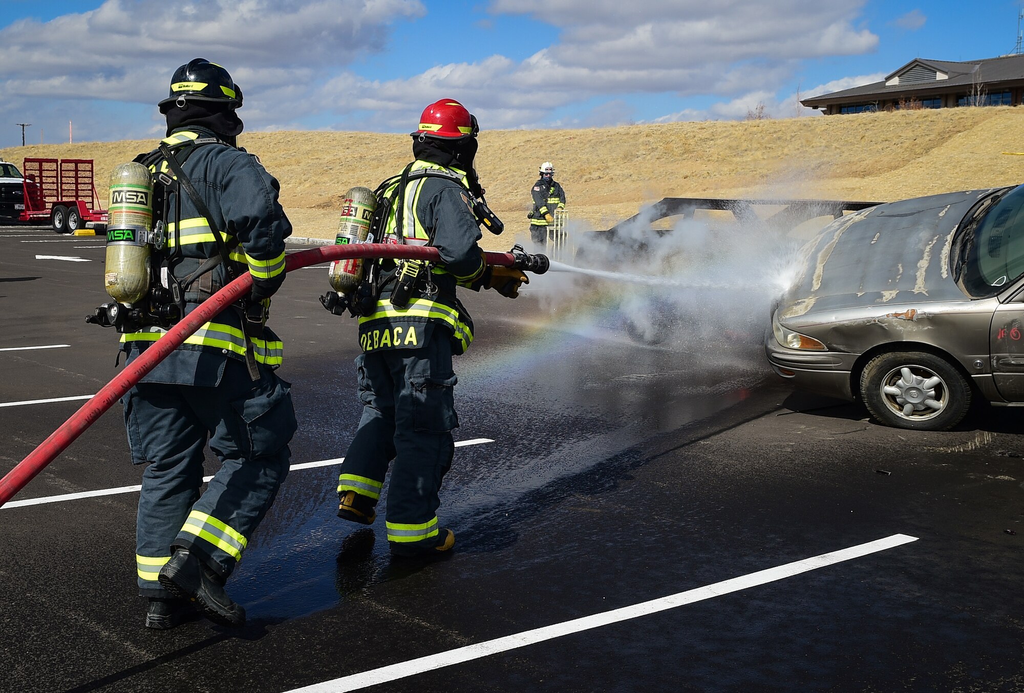 Fire Lt. Christopher Debaca and Dusty Smock, both firefighters from the 460th Civil Engineer Squadron, hose down a burning vehicle during an auto extraction exercise on Buckley Air Force Base, Colo., Feb. 24, 2021.