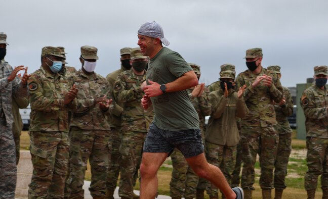 Man runs passed uniformed members while they cheer.