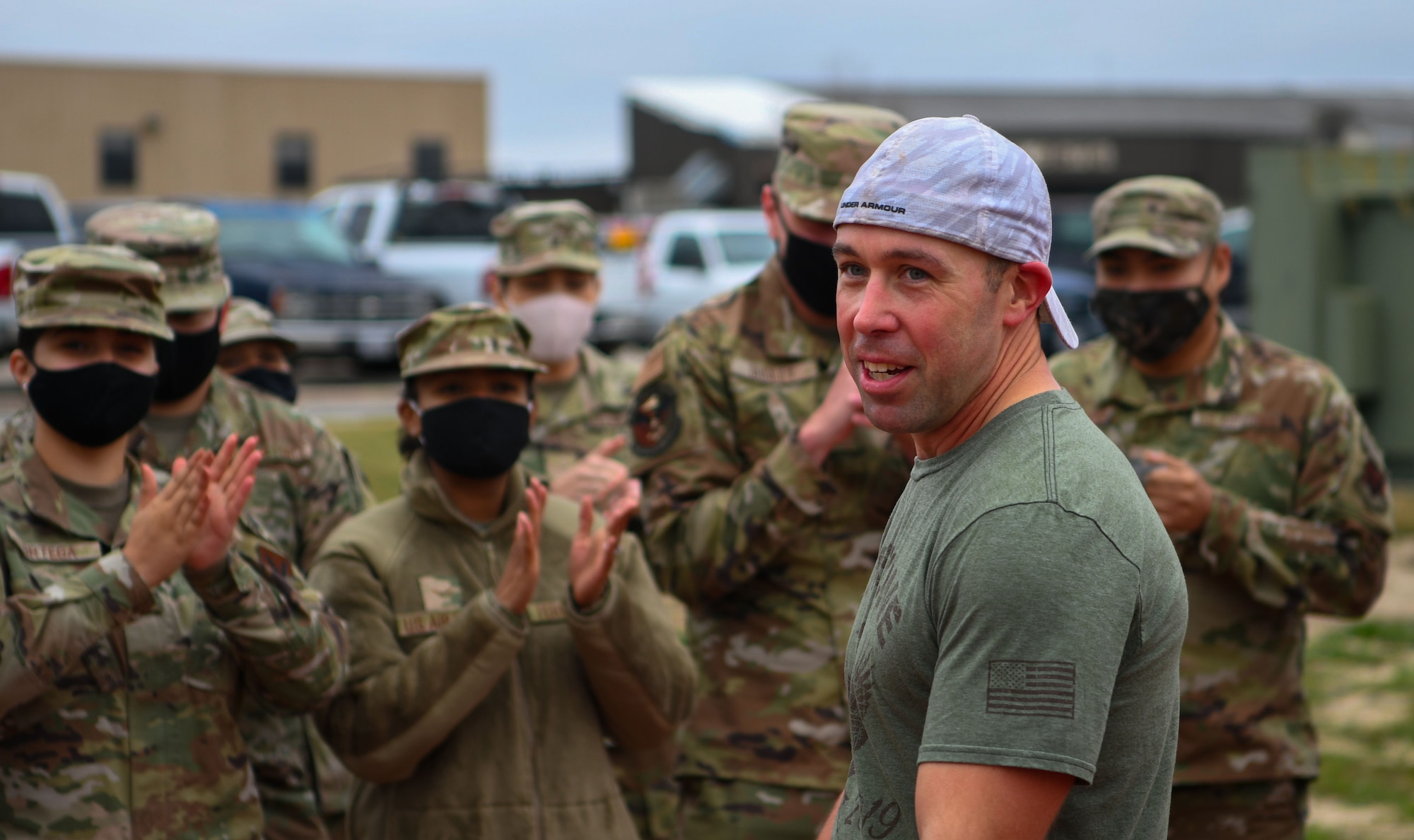 Man stands in front of uniformed members as they applaud him