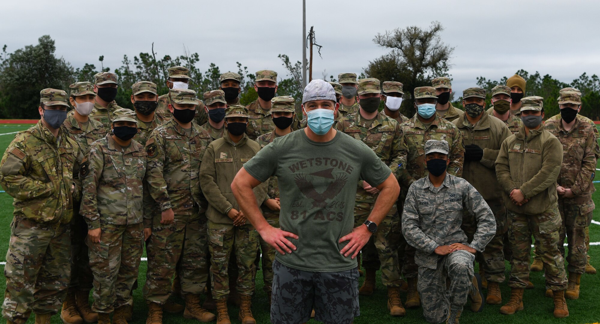 Man stands in front of a group of uniformed members posing for a photo