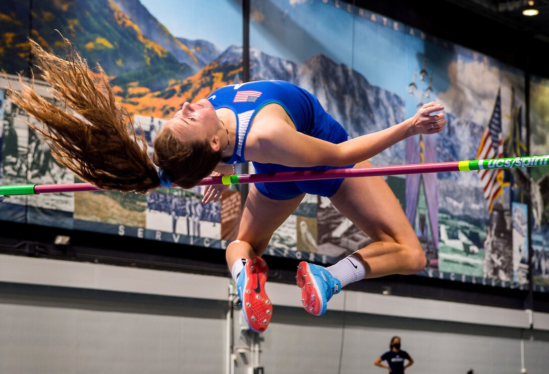 A woman arches her back as she jumps over a high bar.