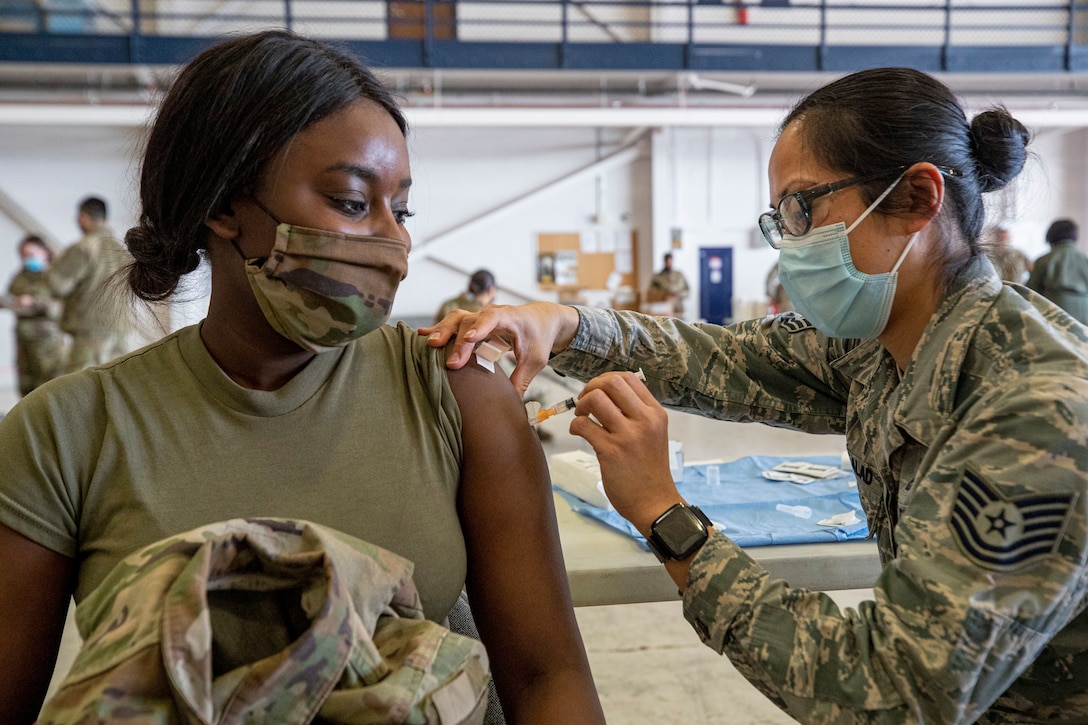 An airman vaccinates a soldier.
