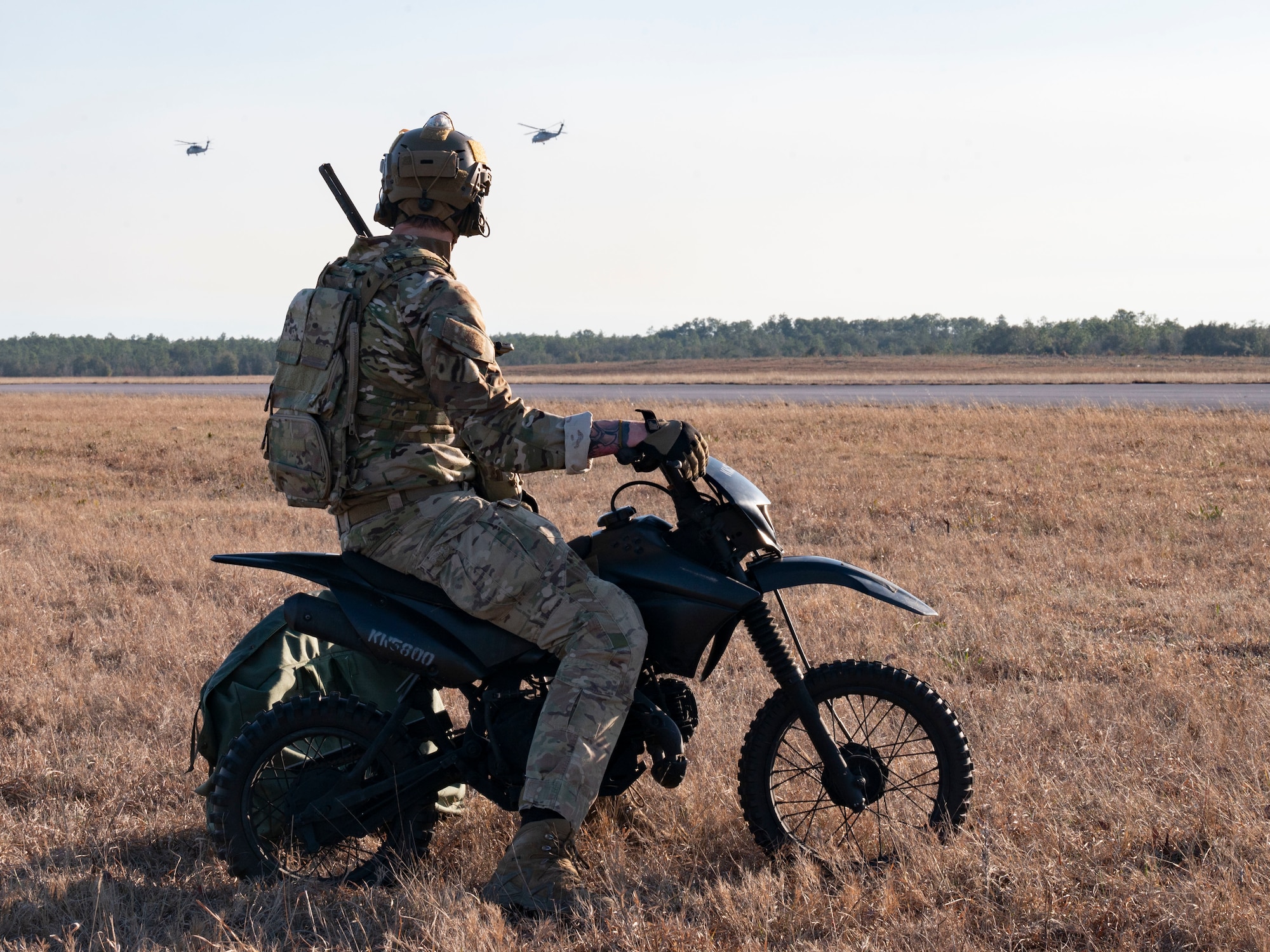 A U.S. Air Force Special Tactics operator, assigned to the 24th Special Operations Wing, watches U.S. Navy MH-60 Sea Hawk Helicopters, assigned to Helicopter Sea Combat Squadron (HSC) 9, prepare to land on an airfield during Emerald Warrior 21.1, at the Eglin Range Complex, Florida, Feb. 23, 2021. Emerald Warrior is the largest joint special operations exercise involving U.S. Special Operations Command forces training to respond to various threats across the spectrum of conflict. (U.S. Air Force photo by Senior Airman Edward Coddington)