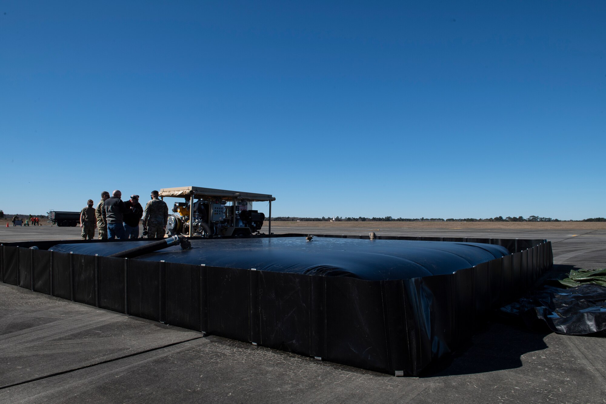 A photo of Airmen standing next to a STARCART and fuel bladder.