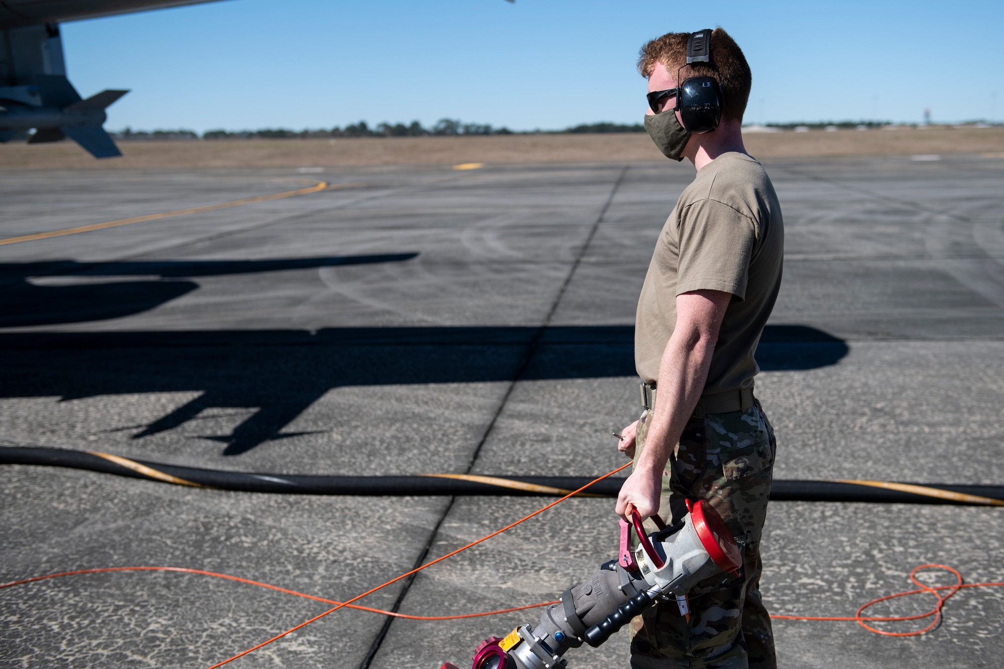 A photo of an Airman holding a fuel hose.
