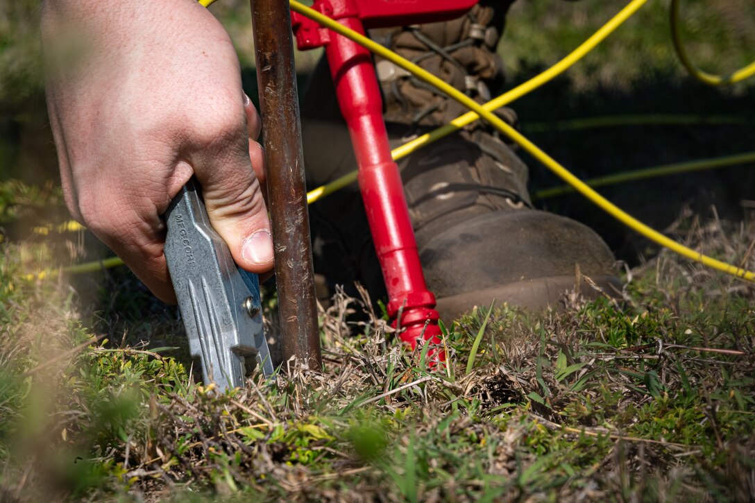 Photo of an Airman attaching an alligator clip to a grounding rod