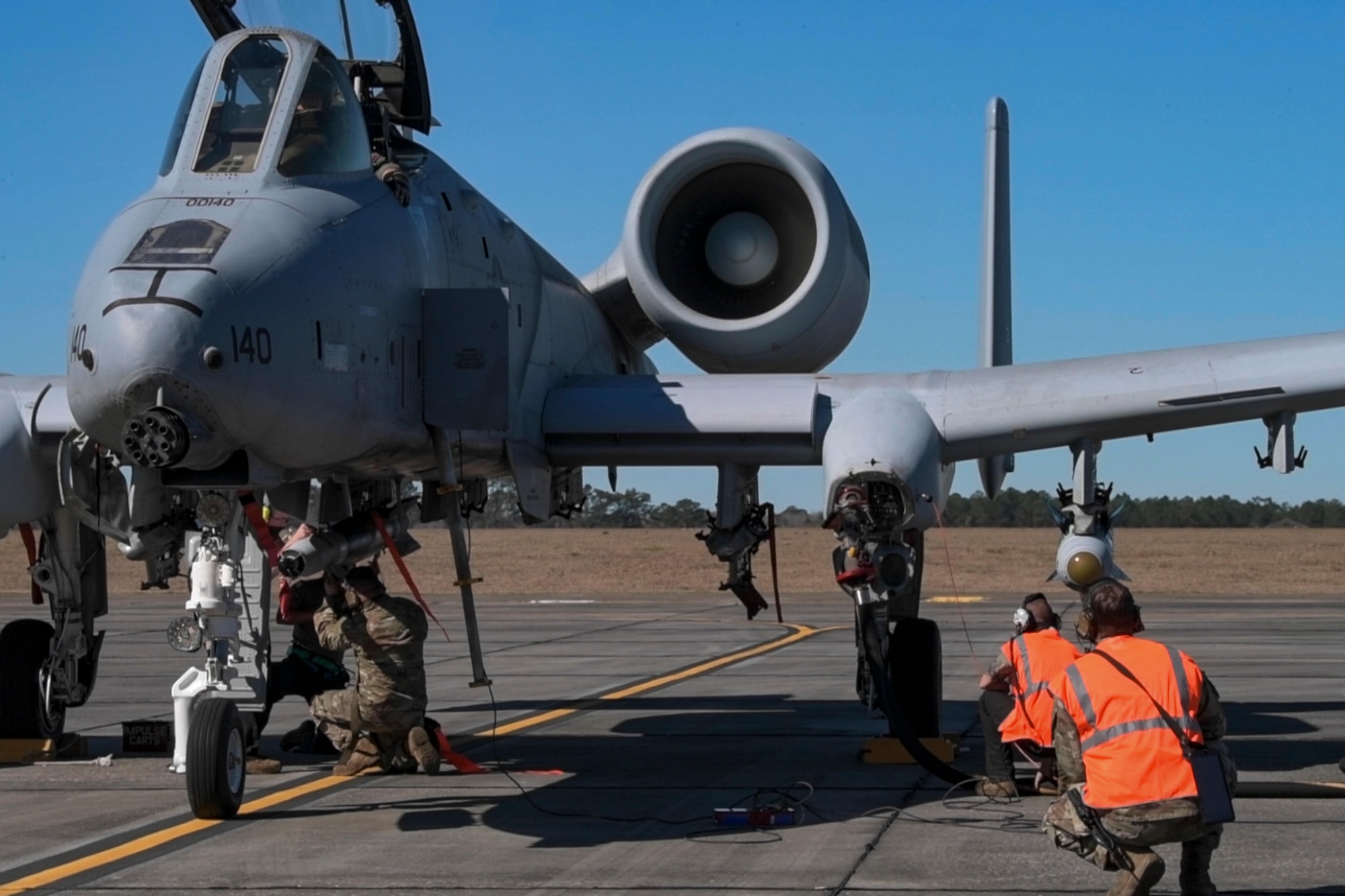 A photo of four airmen standing next to an A-10C Thunderbolt II.