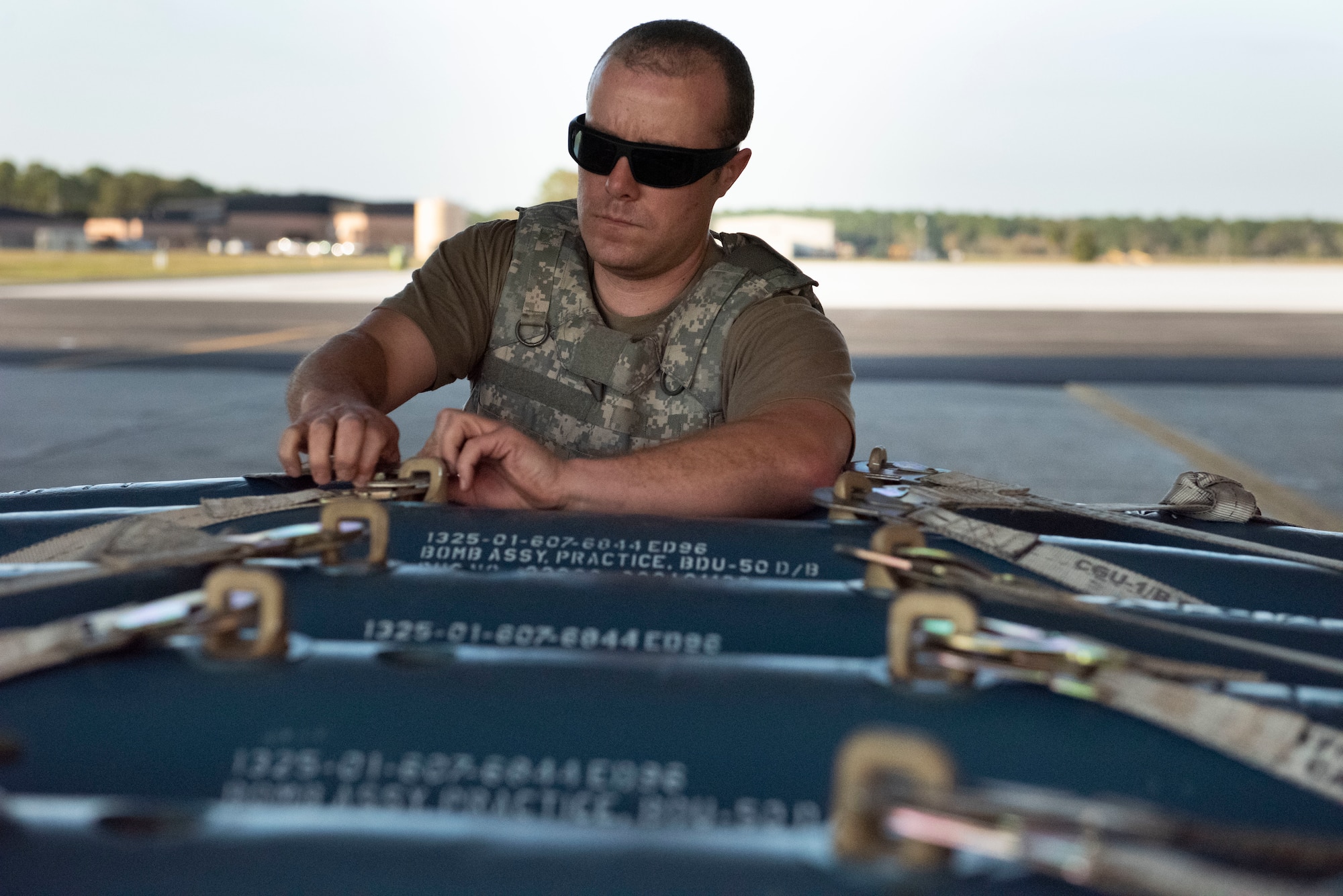 Photo of an Airman removing a strap from a bomb