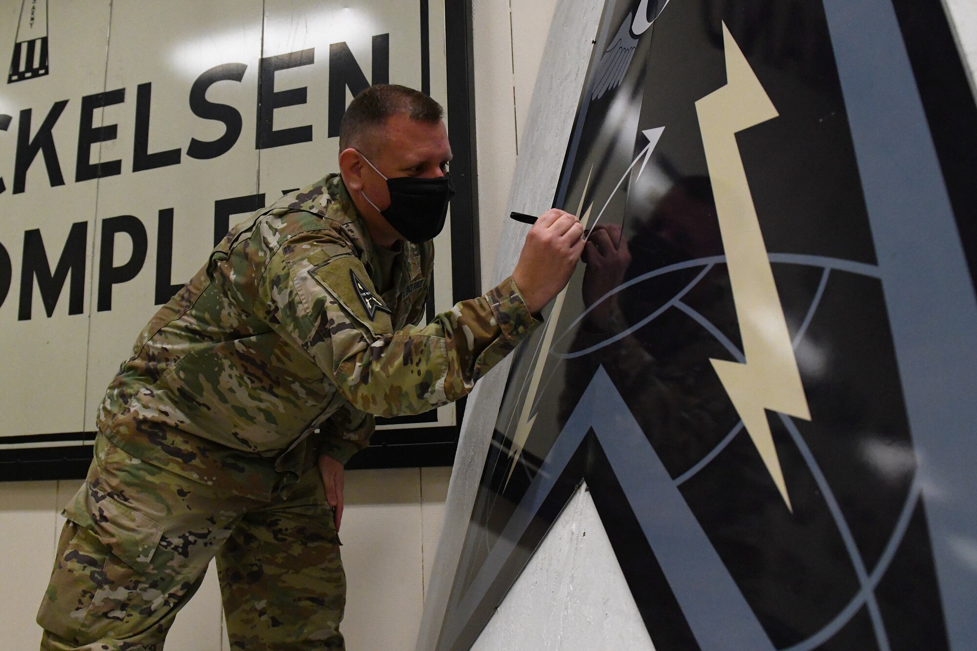 U.S. Space Force Col. Richard Bourquin, Space Delta 4 commander, signs his name on a DEL 4 emblem at Cavalier Air Force Station, N.D., Feb. 22, 2021. The 10th Space Warning Squadron has a tradition of immortalizing all the members that visit or work at the station. (U.S. Space Force photo by Airman 1st Class Andrew Garavito)