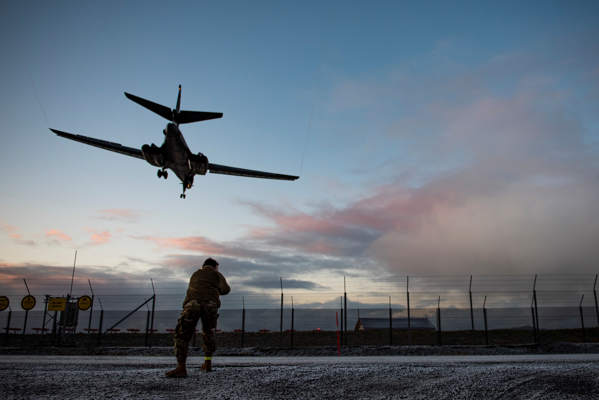 A 9th Expeditionary Bomb Squadron public affairs specialist documents a B-1B Lancer landing at Ørland Air Force Station, Norway, March 3, 2021. Integrating with NATO allies and partners enhances interoperability while also improving command and control mechanisms. (U.S. Air Force photo by Airman 1st Class Colin Hollowell)