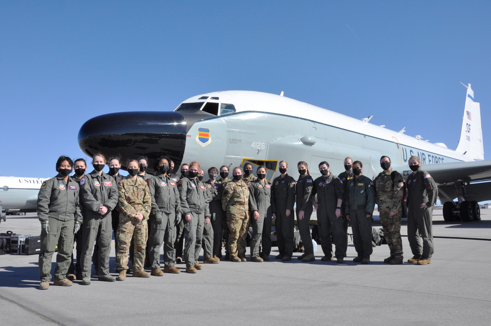 a group of 23 women air crew and support staff in uniform standing together in front of an RC-135 Rivet Joint aircraft