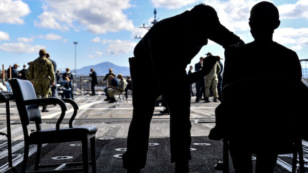 Sailors assigned to the Ticonderoga-class guided-missile cruiser USS Lake Champlain (CG 57) receive the COVID-19 vaccine in the ship's hangar bay.