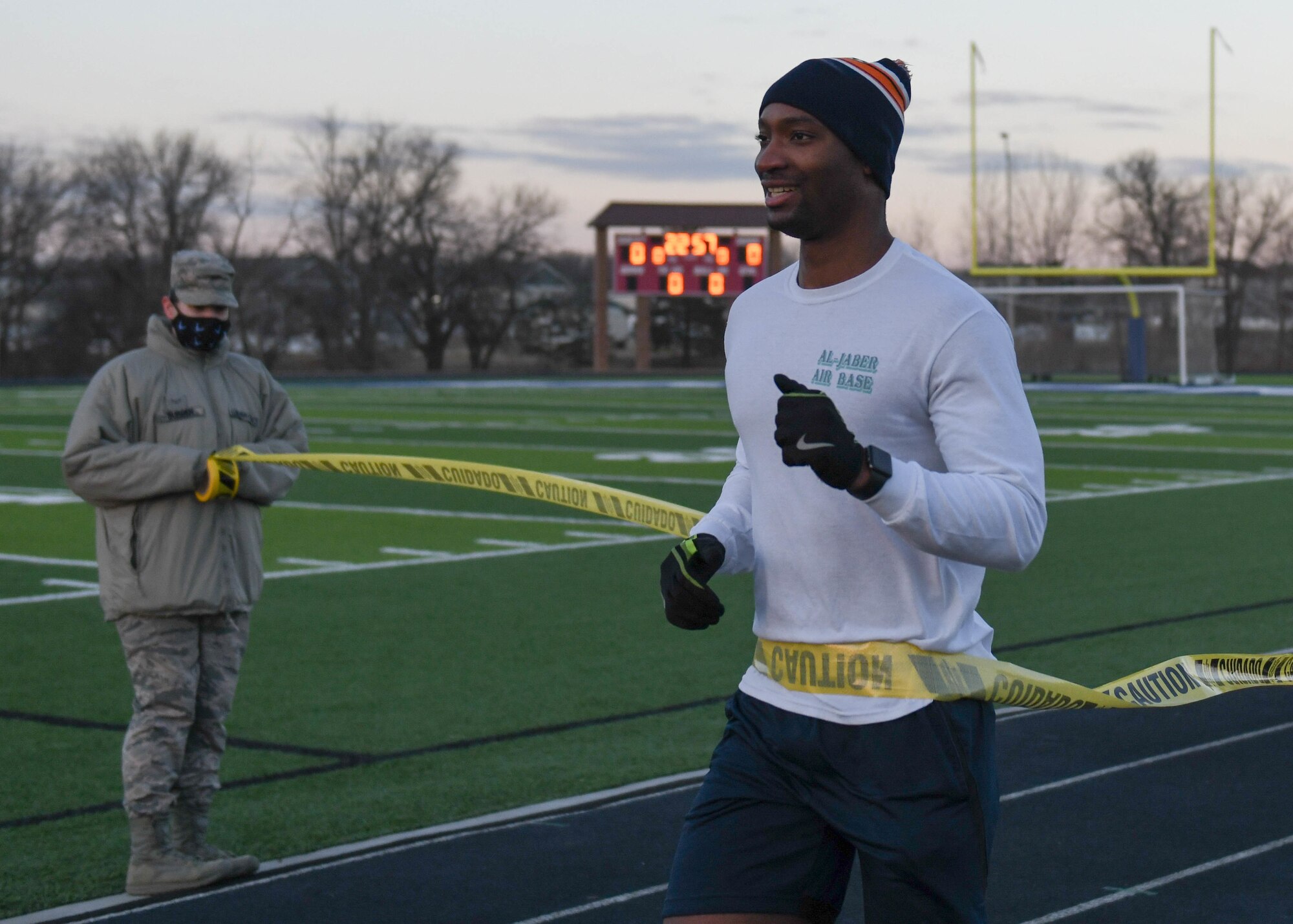 An Airman crosses the finish line to the Great American Spit Out 5k at the track.