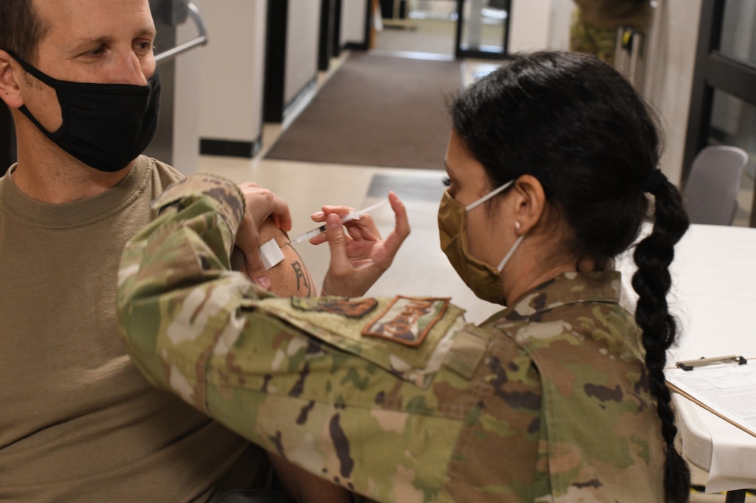 U.S. Air Force Col. David ‘Moon’ Halasi-Kun, vice-commander, 104th Fighter Wing, receives his COVID-19 vaccination from Staff Sgt. Daniela Rizzari, aeromedical technician, 104th Medical Group, at the base clinic on Feb. 23, 2021. Barnestormers have been stepping up to fight the COVID-19 pandemic by volunteering to get vaccinated. (U.S. Air National Guard photo by Staff Sgt. Hanna Smith)