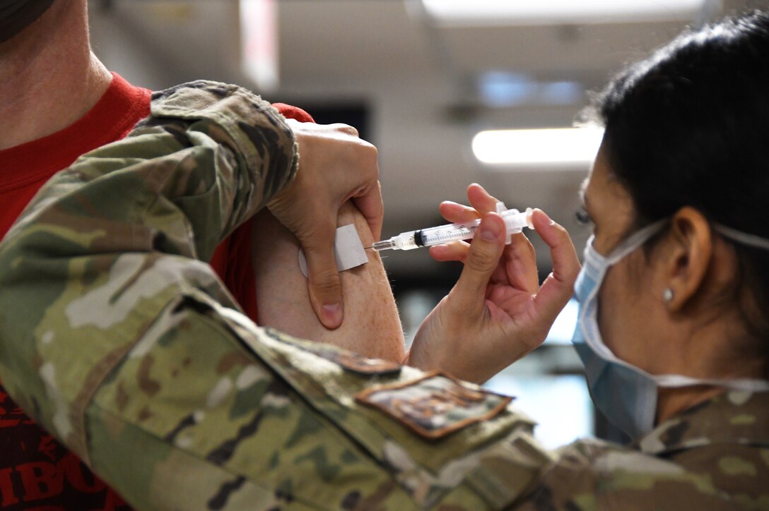 U.S. Air Force Lt. Col. Eric ‘Sherman’ Armentrout, a pilot with the 131st Fighter Squadron, receives his COVID-19 vaccination from Staff Sgt. Daniela Rizzari, an aeromedical technician with the 104th Medical Group, at the base clinic Feb. 5. 2021. Barnestormers have been stepping up to fight the COVID-19 pandemic by volunteering to get vaccinated.(U.S. Air National Guard photo by Staff Sgt. Hanna Smith)