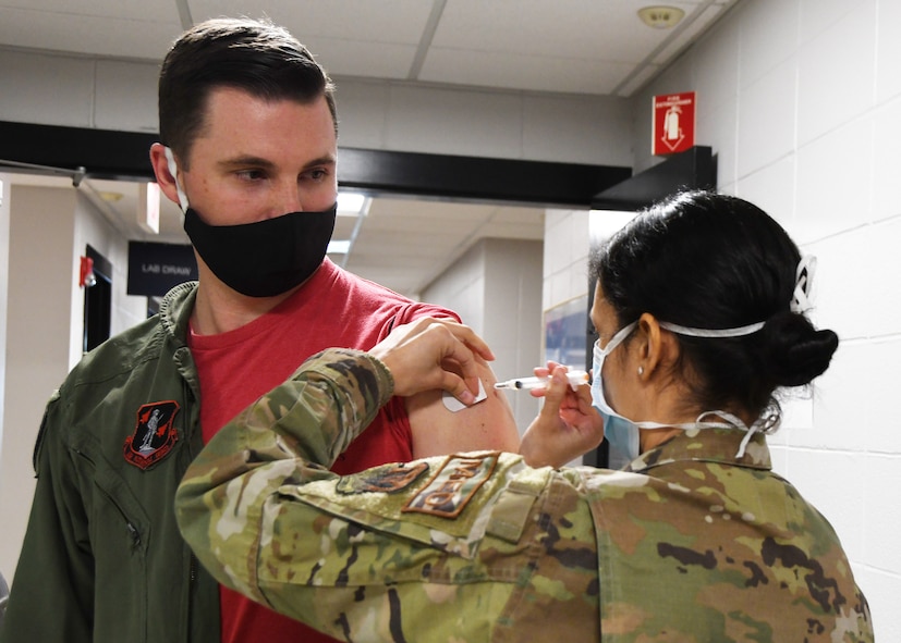 U.S. Air Force Maj. Michael ‘BS’ Walsh, a pilot with the 131st Fighter Squadron, receives his COVID-19 vaccination from Staff Sgt. Daniela Rizzari, an aeromedical technician with the 104th Medical Group, at the base clinic Feb. 5, 2021. Barnestormers have been stepping up to fight the COVID-19 pandemic by volunteering to get vaccinated.(U.S. Air National Guard photo by Staff Sgt. Hanna Smith)