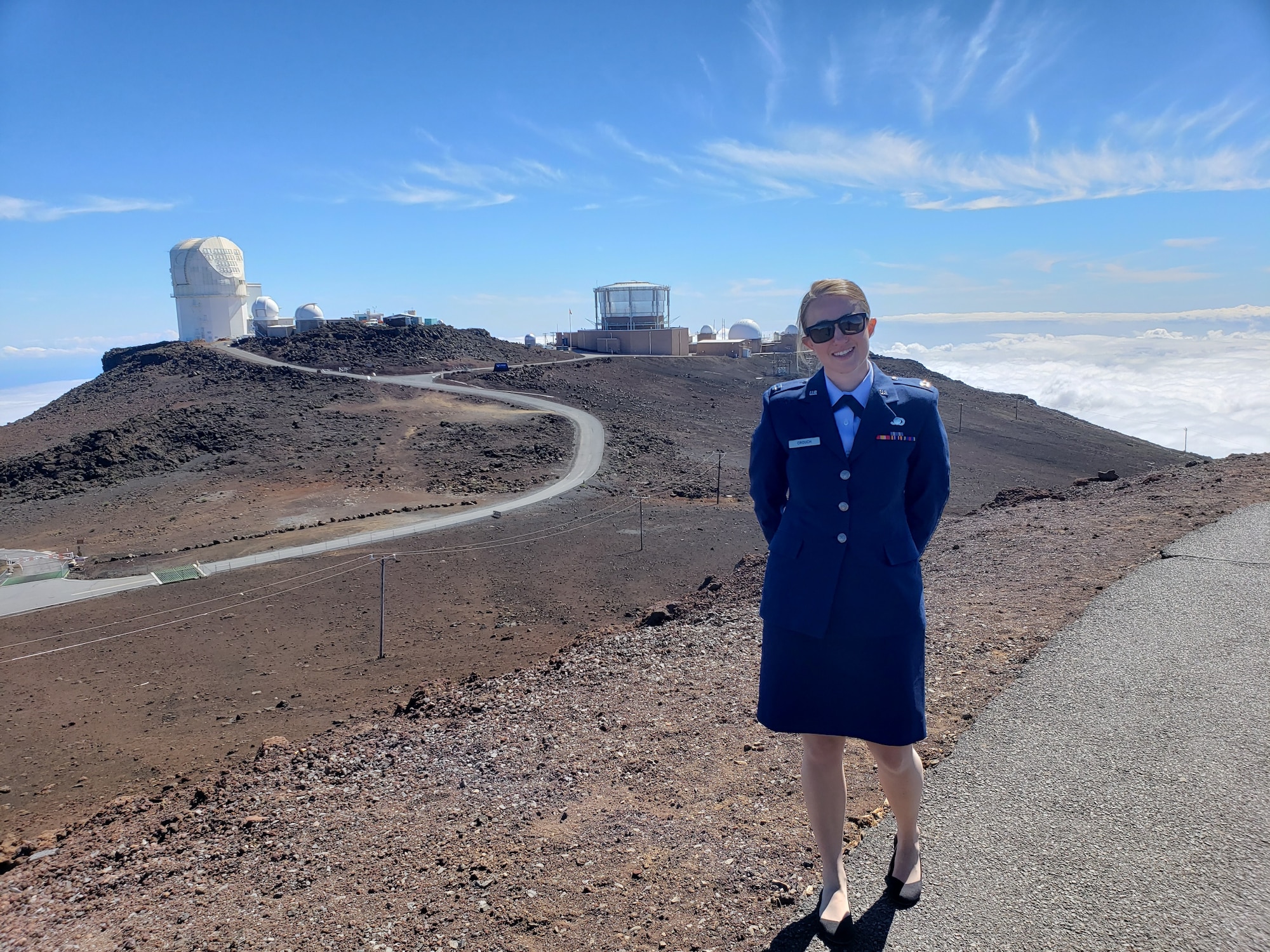 Air Force Research Laboratory engineer Capt. Tara Crouch with AFRL’s Maui Space Surveillance Complex in the background. The MSSC, located on Maui’s Haleakala Summit, is home to the DOD's largest optical telescope, the 3.6-meter Advanced Electro-Optical System. (Courtesy photo)