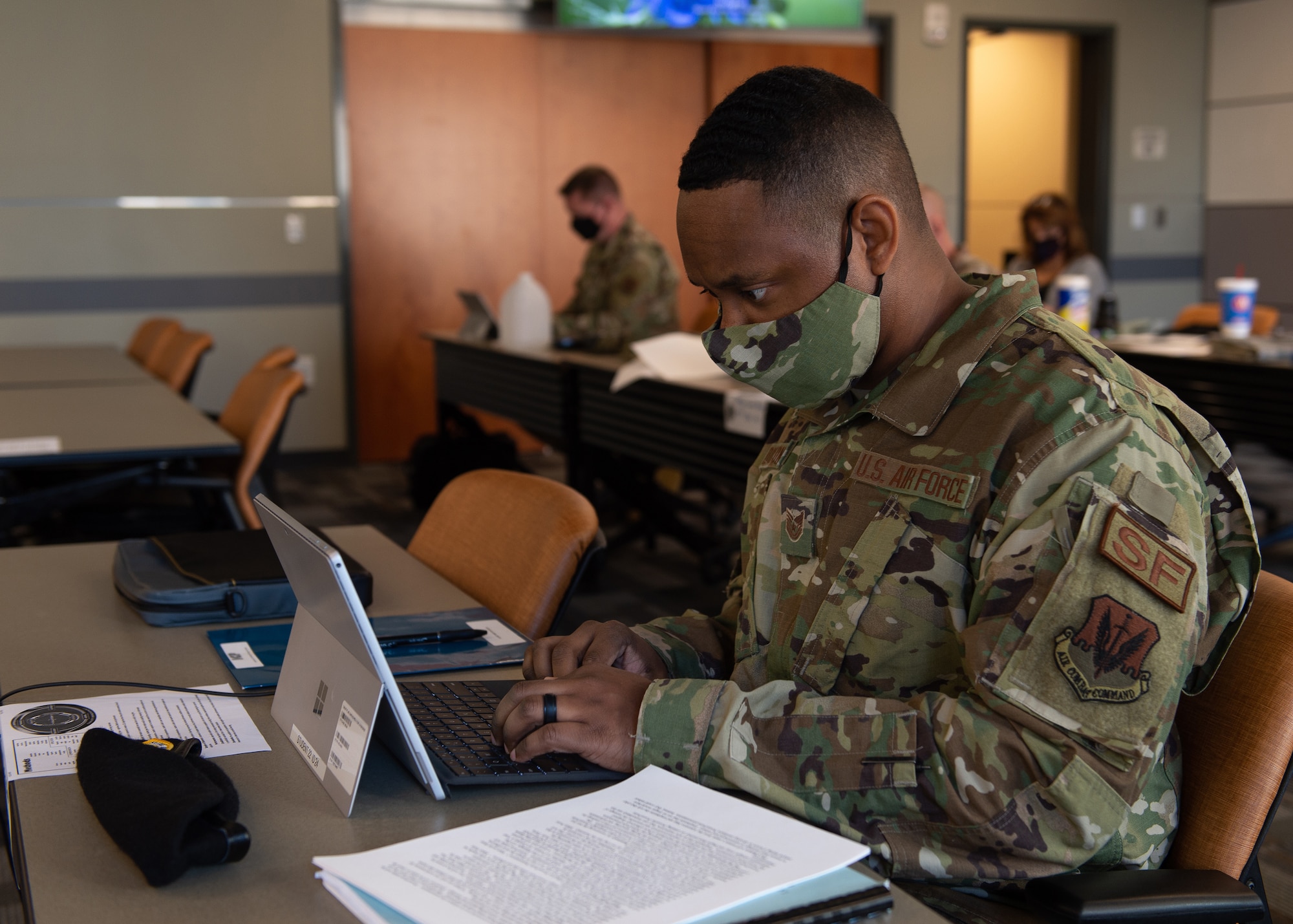 an Airman types at a laptop in a classroom.