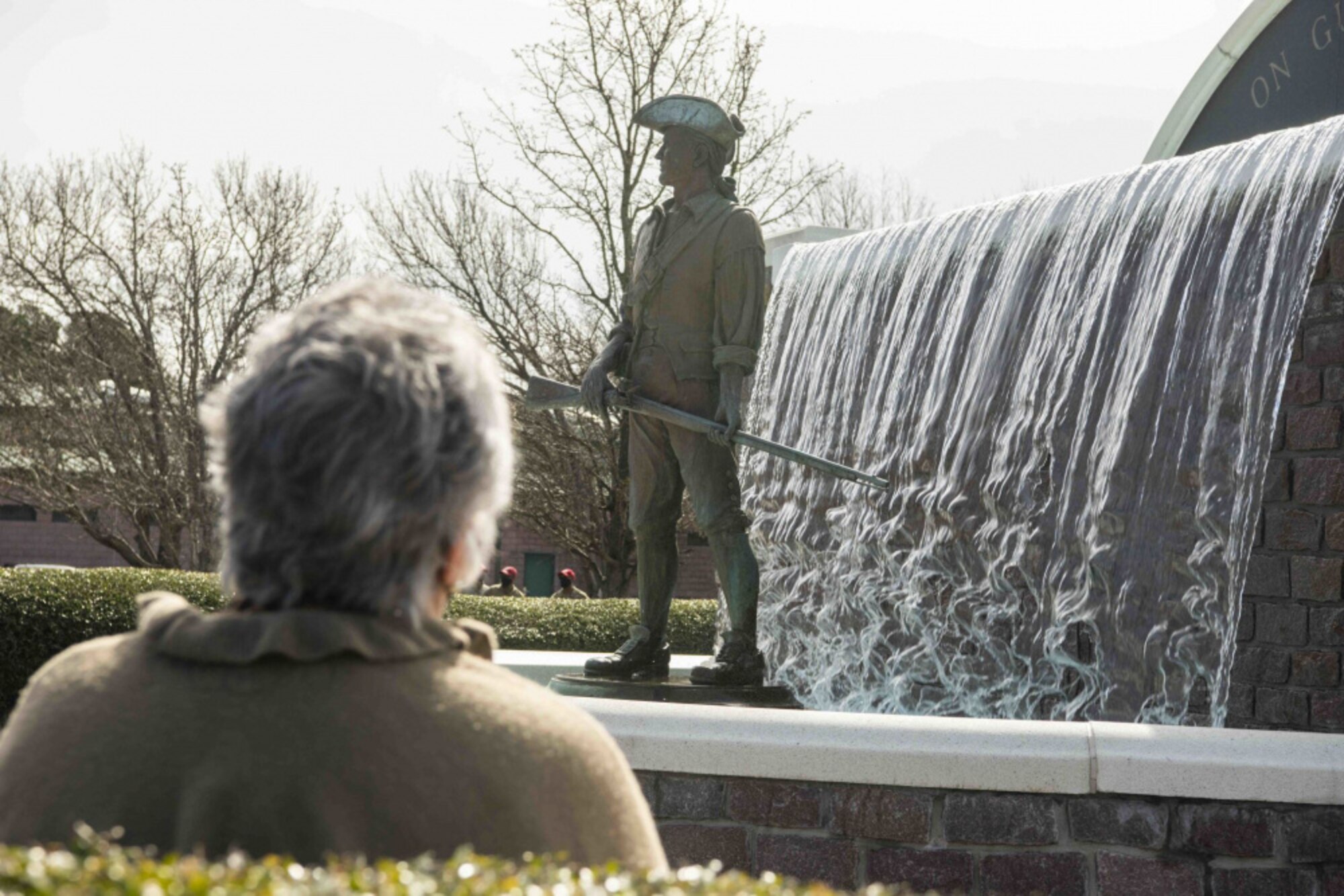 A woman sits near a reflecting waterfall