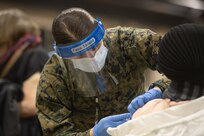 U.S. Navy Hospital Corpsman 1st Class Ashley Barker, a Grand Rapids, Michigan, native with Combat Logistics Battalion 22 (CLB-22), administers a COVID-19 vaccine to a local Philadelphia resident during the opening of the state-run, federally-supported Center City Community Vaccination Center at the Pennsylvania Convention Center in Philadelphia, March 3, 2021.