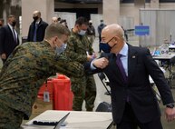 A U.S. Navy Sailor assigned to Combat Logistics Battalion 22 (CLB-22), left, and U.S. Secretary of Homeland Security Alejandro N. Mayorkas, right, exchange greetings during the soft launch of the state-run, federally-supported Center City Community Vaccination Center at the Pennsylvania Convention Center in Philadelphia on Mar. 2, 2021.
