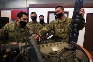 Senior Master Sgt. Matthew Parker, 349th Maintenance Group quality assurance superintendent, right, explains how to conduct a compression test to Airmen assigned to Beale Air Force Base preparing to take the Airframe and Powerplant exam, Feb. 16, 2021, at Travis Air Force Base, California. The Airmen visited Travis to learn about the various components on different types of aircraft. (U.S. Air Force photo by Airman 1st Class Luis A. Ruiz-Vazquez)