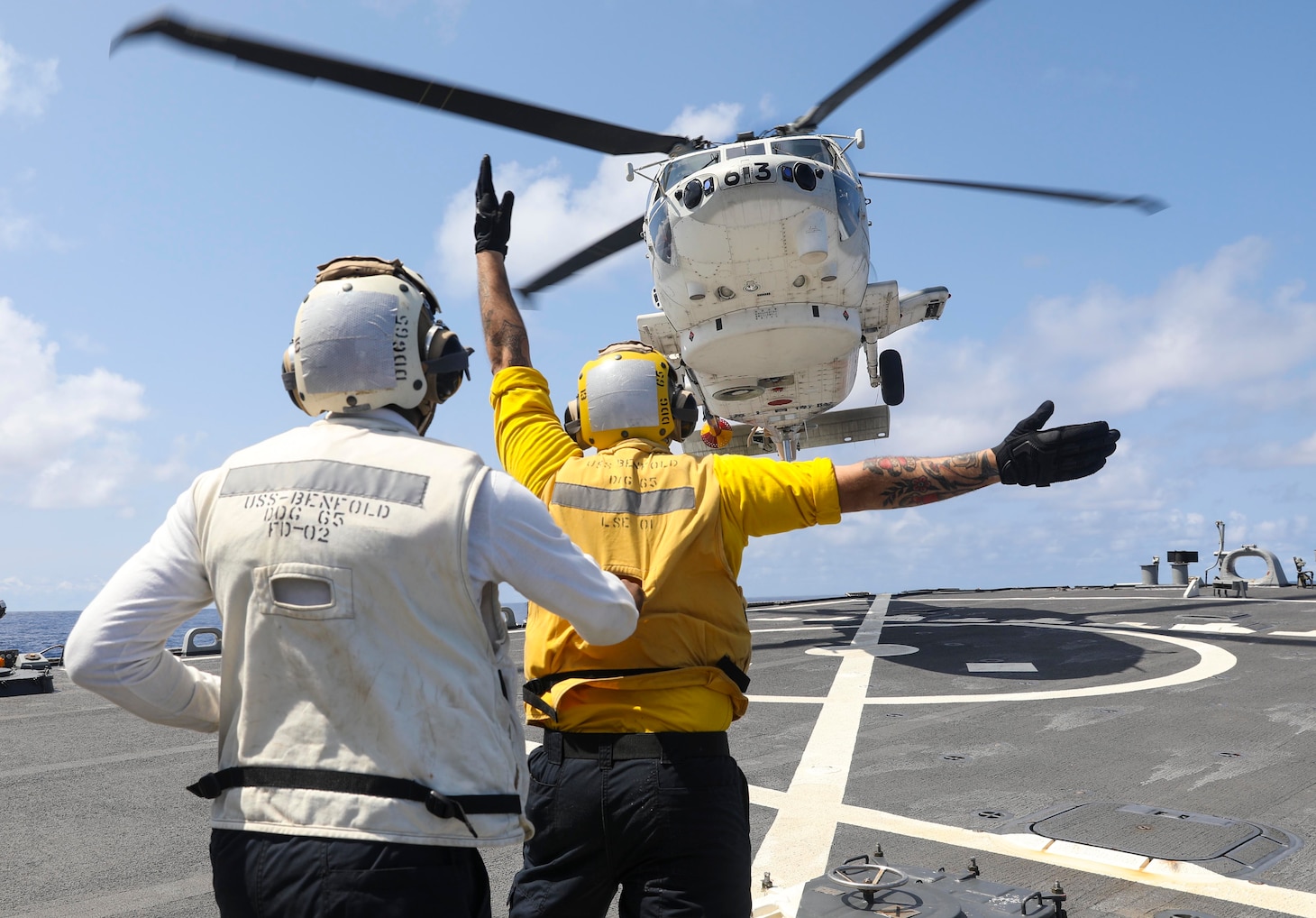 210304-N-FO714-2023 PHILIPPINE SEA (March 4, 2021) - Boatswain’s Mate 2nd Class Dane Potzinger, from Ada, Mich., signals a Japan Maritime Self Defense Force SH-60 Seahawk to land on the flight deck of the Arleigh Burke-class guided-missile destroyer USS Benfold (DDG 65) while Boatswain’s Mate 1st Class Glenrick Henry, from Bronx, N.Y., spots for safety during the annual U.S.-Japan Bilateral Advanced Warfighting Training Exercise. BAWT focuses on joint training and interoperability of coalition forces, and enables real-world proficiency and readiness in response to any contingency. (U.S. Navy photo by Mass Communication Specialist 2nd Class Deanna C. Gonzales)