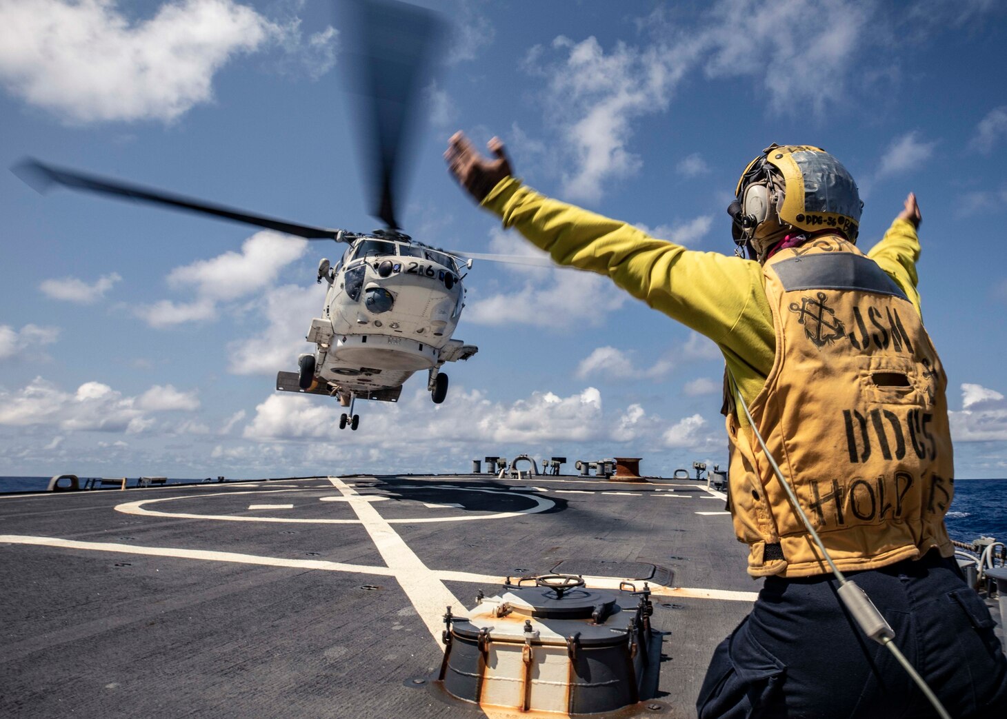 210304-N-HI376-1163 PHILIPPINE SEA (March 4, 2021) -  Boatswain’s Mate 3rd Class Zachary Kai signals to a Japan Maritime Self-Defense Force (JMSDF) SH-60 Seahawk assigned to the JS Ise (DDH 182) on the flight deck of the Arleigh Burke-class guided-missile destroyer USS John S. McCain (DDG 56) during the annual U.S.-Japan Bilateral Advanced Warfighting Training exercise. BAWT focuses on joint training and interoperability of coalition forces, and enables real-world proficiency and readiness in response to any contingency. (U.S. Navy photo by Mass Communication Specialist 1st Class Jeremy Graham)