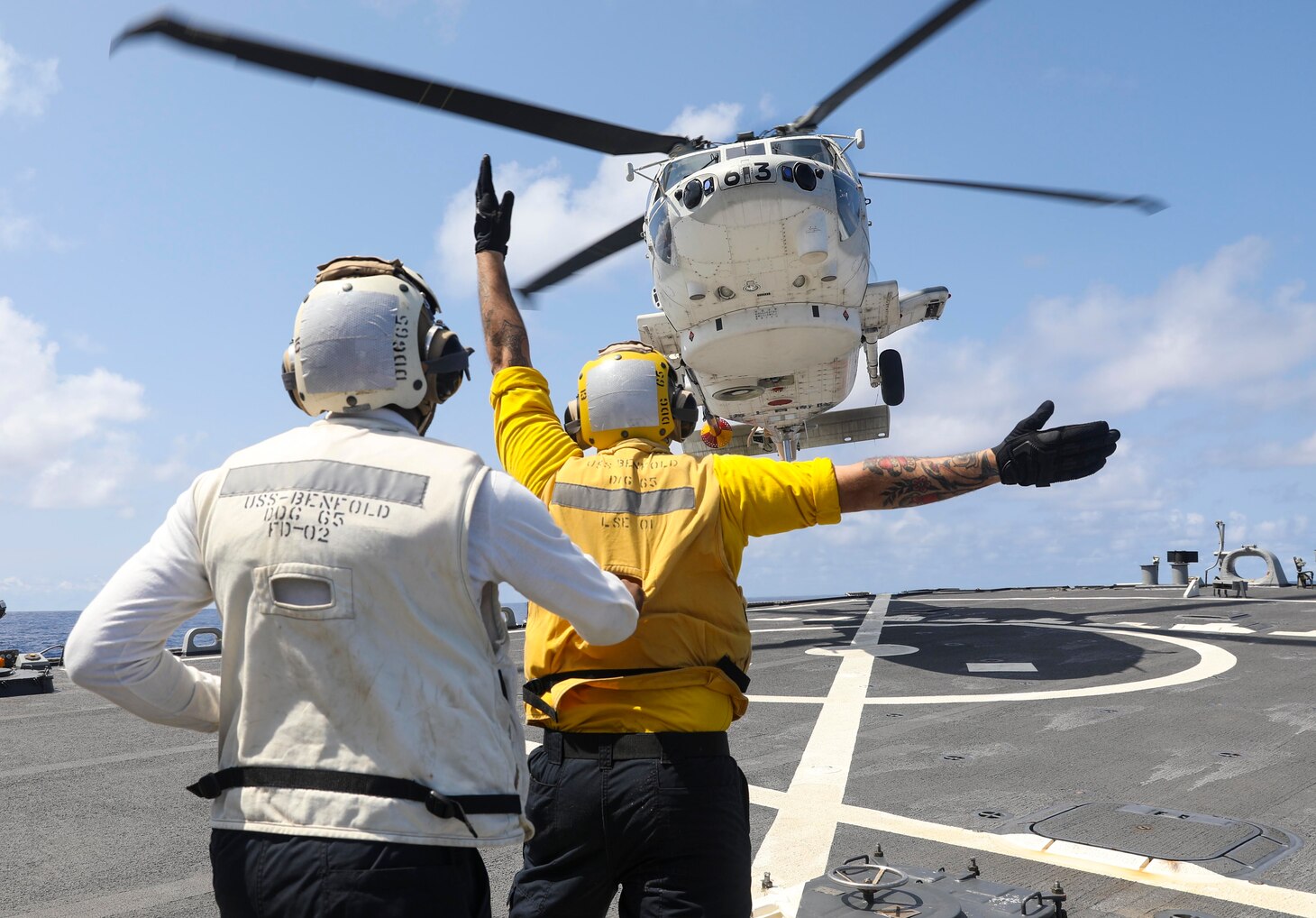 Boatswain’s Mate 2nd Class Dane Potzinger, from Ada, Mich., signals a Japan Maritime Self Defense Force SH-60 Seahawk to land on the flight deck of the Arleigh Burke-class guided-missile destroyer USS Benfold (DDG 65).