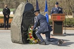 An honor guard Airman lays a wreath in front of a memorial