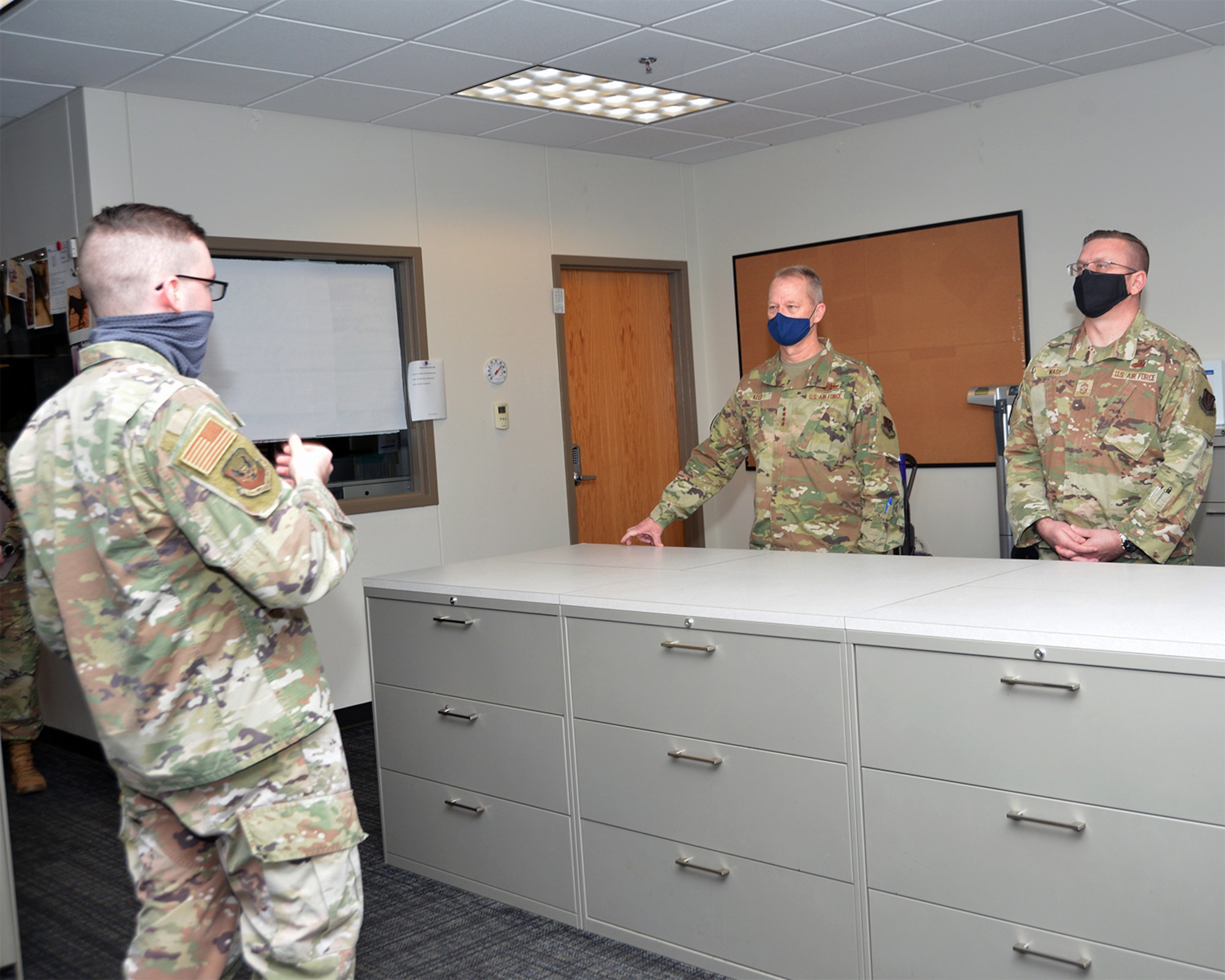 An officer in uniform briefs leadership in uniform in a room.