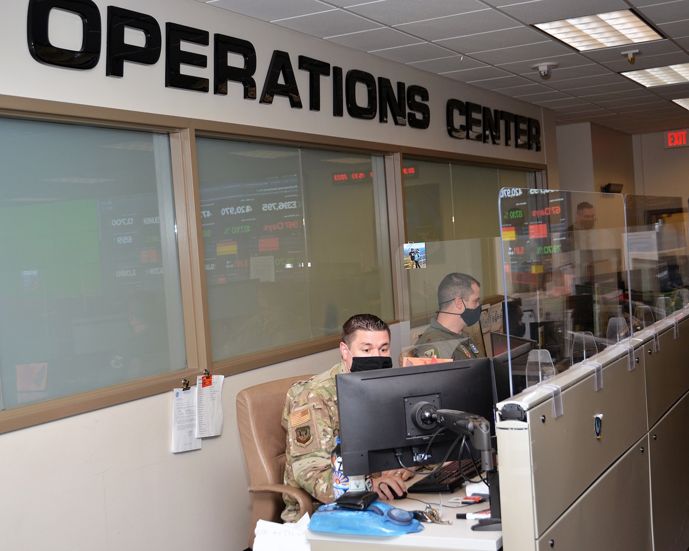 Airmen in uniform type on computers in an operations center.