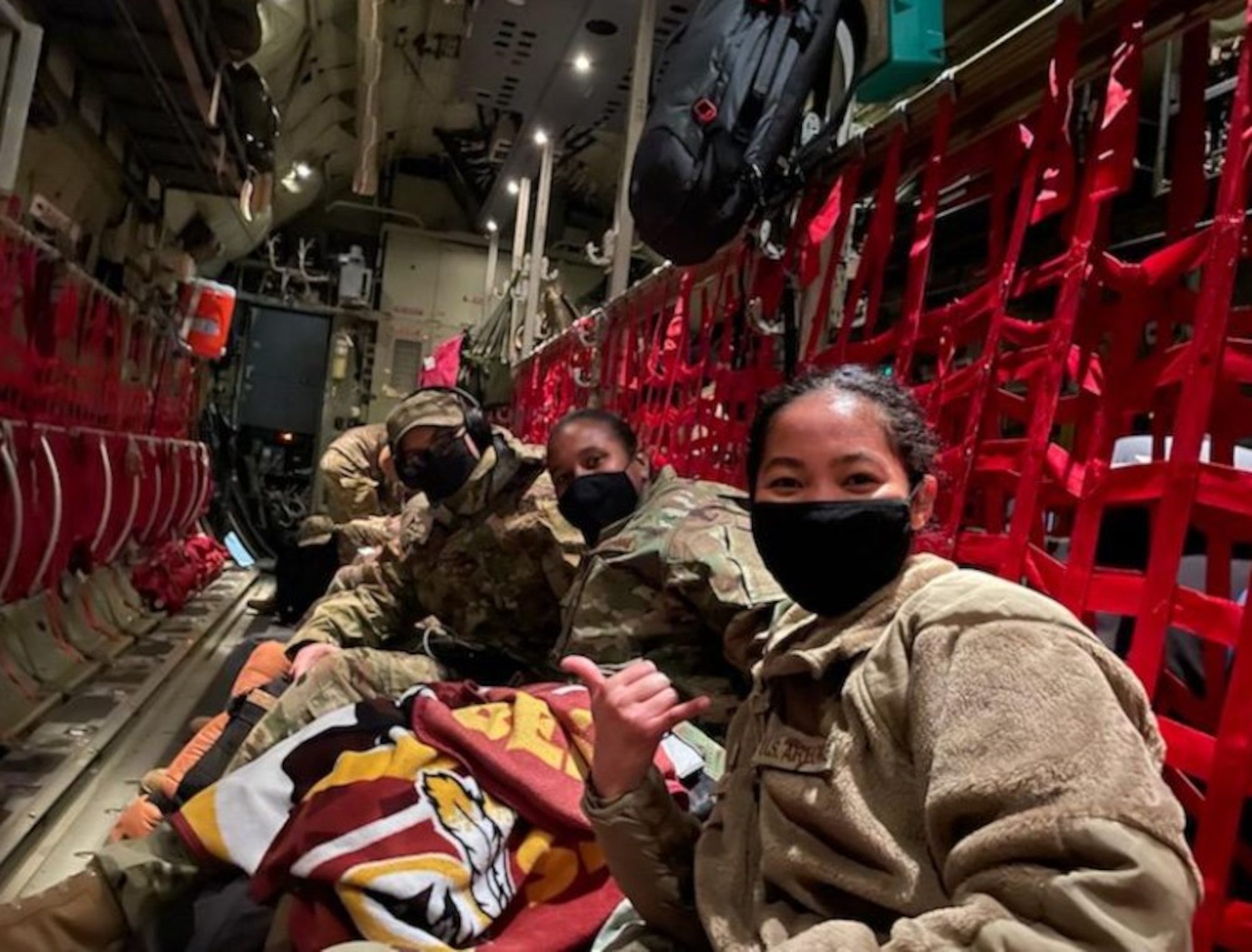 U.S. Air Force Senior Airmen Sergio Porto-Duarte, far left, 776th Expeditionary Air Base Squadron weather forecaster, Master Sgt. Melissa Thomas, center, 776th EABS weather flight chief, and Airman 1st Class Marisa Paʻaʻāina, right, 776th EABS weather forecaster, pose for a photo on a C-130 from Ramstein Air Base, Germany, Jan. 20, 2021.