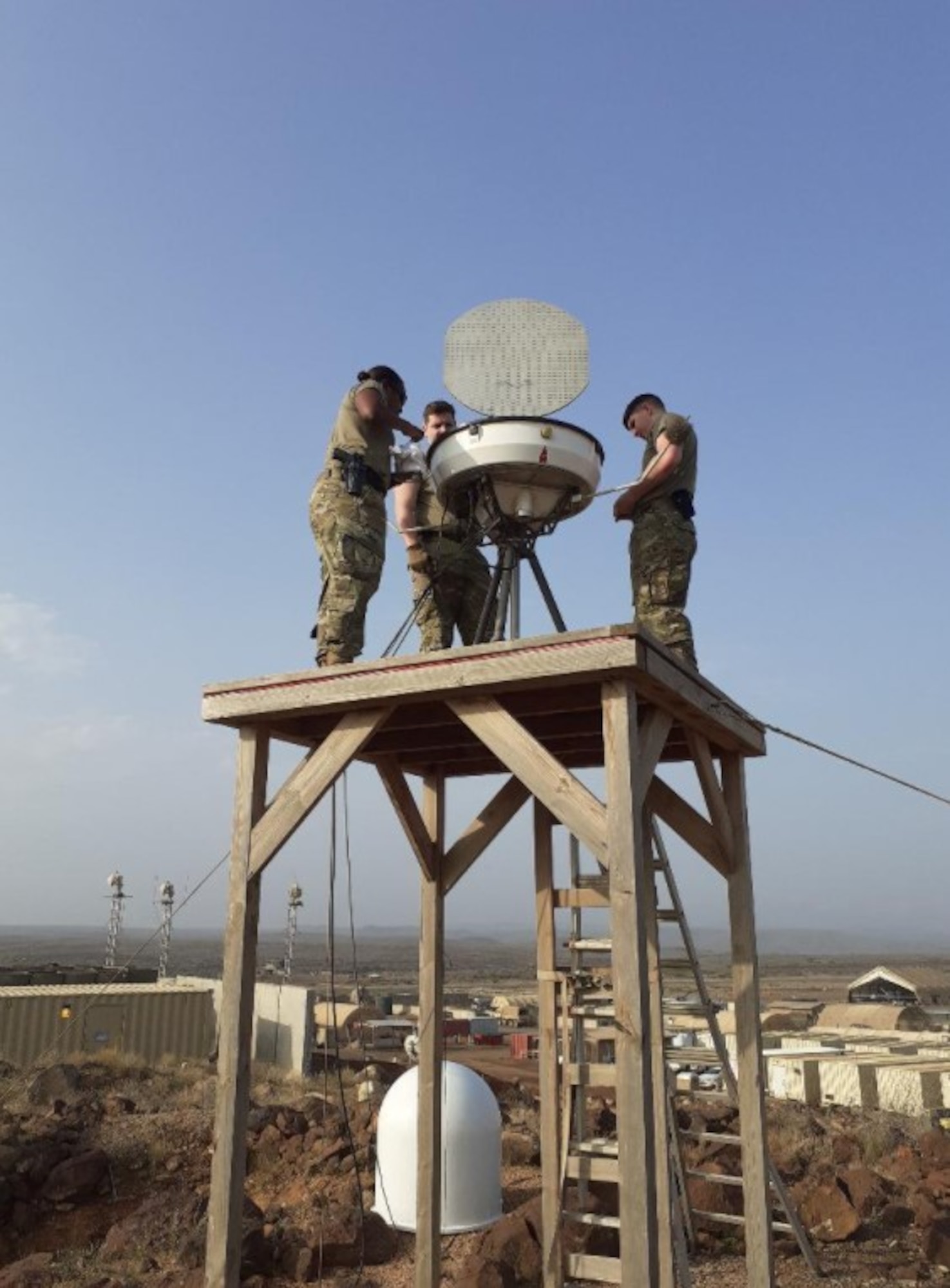 U.S. Air Force Master Sgt. Melissa Thomas, left, 776th Expeditionary Air Base Squadron weather flight chief, and the Chabelley radar, airfield and weather systems team inspect and complete maintenance on the Portable Doppler Radar at Camp Lemonnier, Djibouti, Feb. 24, 2021.