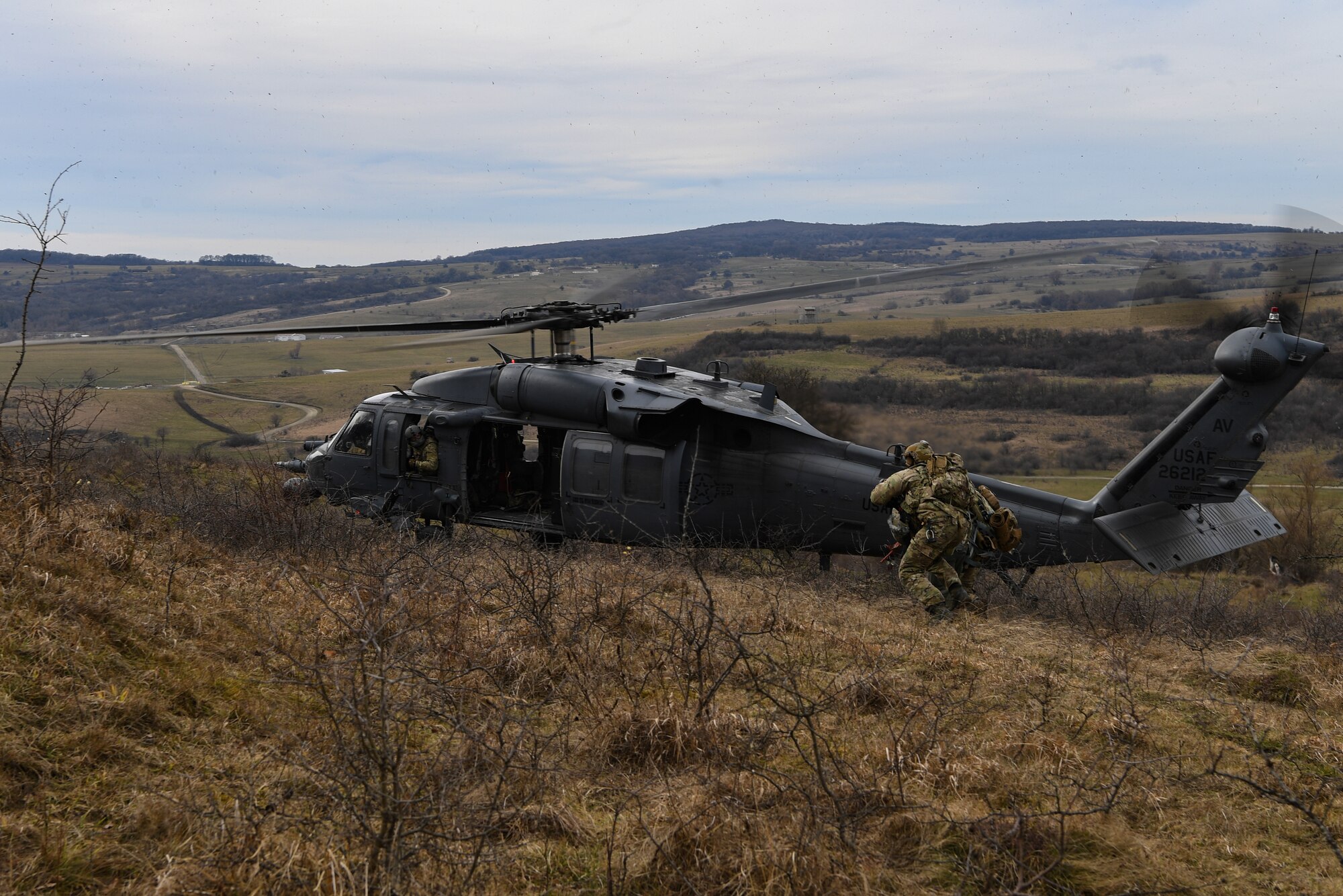 Two pararescuemen escort a downed pilot to a U.S. Air Force HH-60G Pave Hawk helicopter during Operation Porcupine in Romania, March 4, 2021.