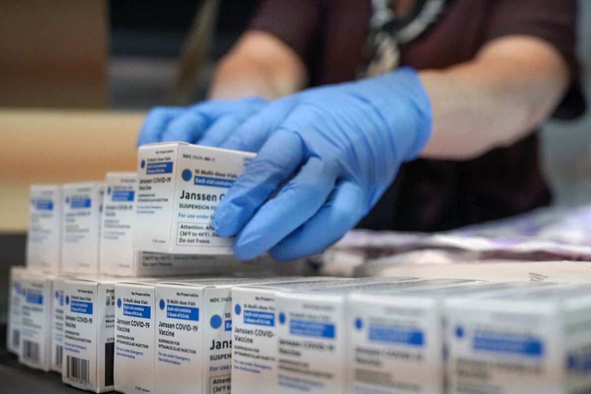 Someone wearing gloves holds a box of the first doses of the Johnson and Johnson vaccines.