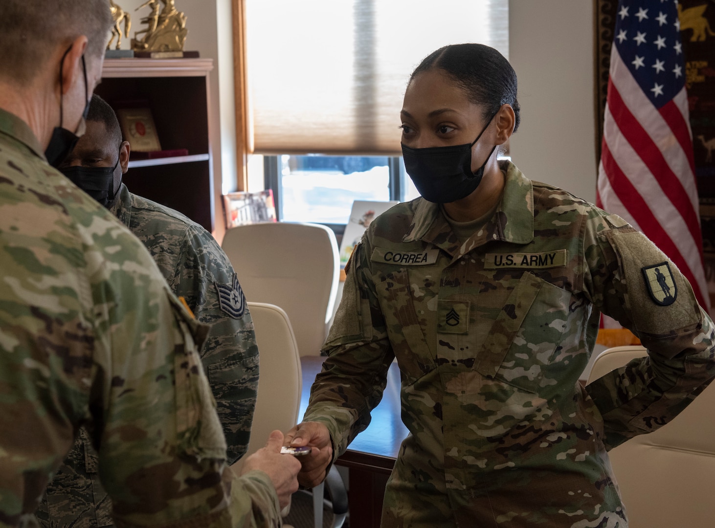Staff Sgt. Selena Correa receives a coin from Gen. Daniel Hokanson during a visit by Hokanson to the Vermont National Guard Joint Task Force Headquarters Feb. 26, 2021. Correa and Air Force Tech. Sgt. Kirby Addison (left) were recognized for their efforts to increase the diversity recruiting and retention efforts as special emphasis program managers for the Vermont Guard. Hokanson is the chief of the National Guard Bureau. (U.S. Army National Guard photo by Don Branum)