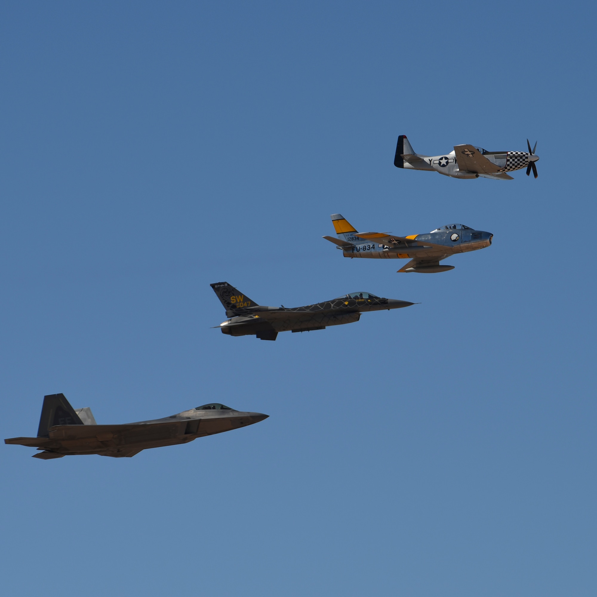 An F-22 Raptor, an F-16 Fighting Falcon, an F-86 Sabre and a P-51 Mustang in flight