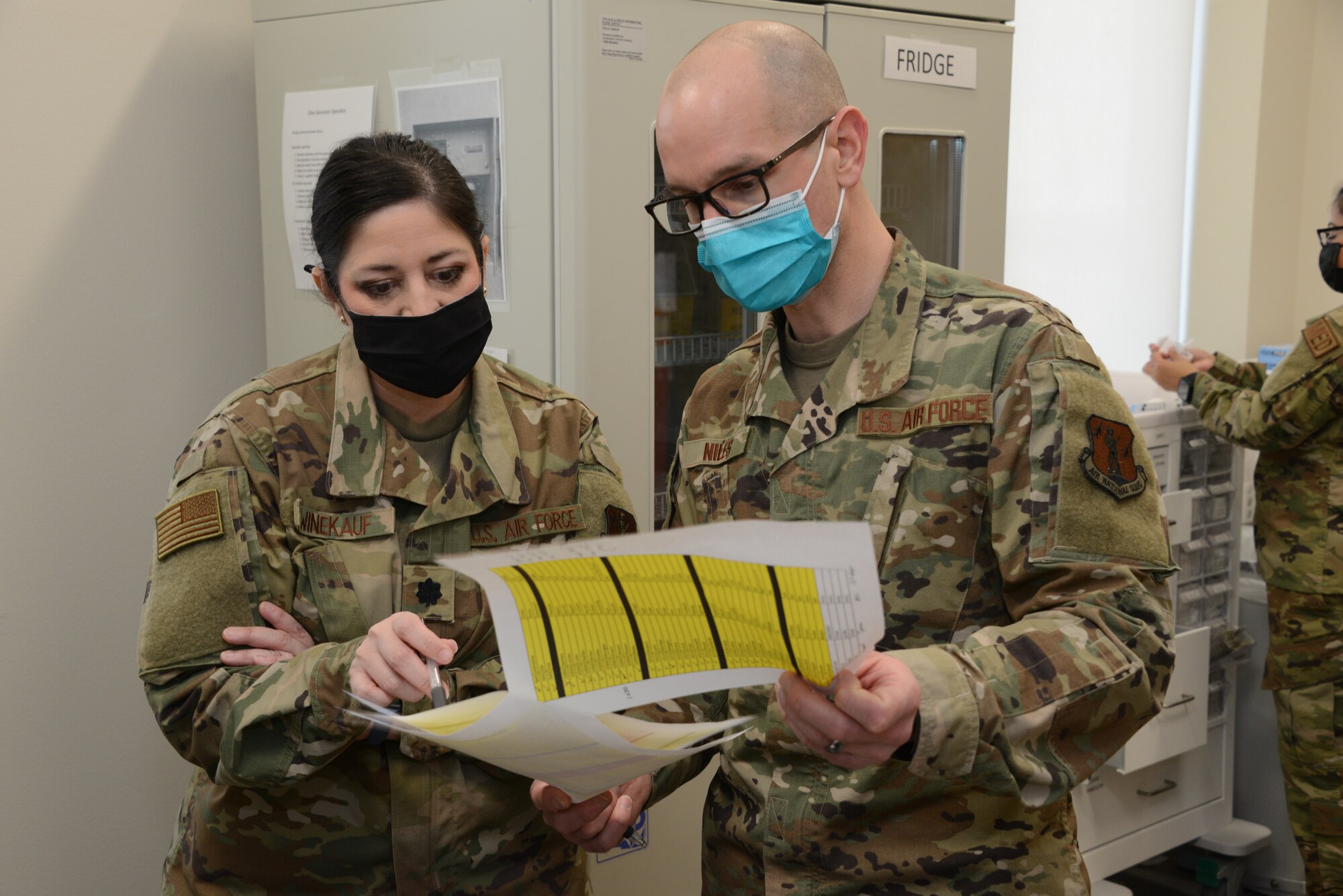 Lt. Col. Tonja Winekauf and Capt. Paul Niles look over a list of patients who are scheduled to receive COVID vaccinations.