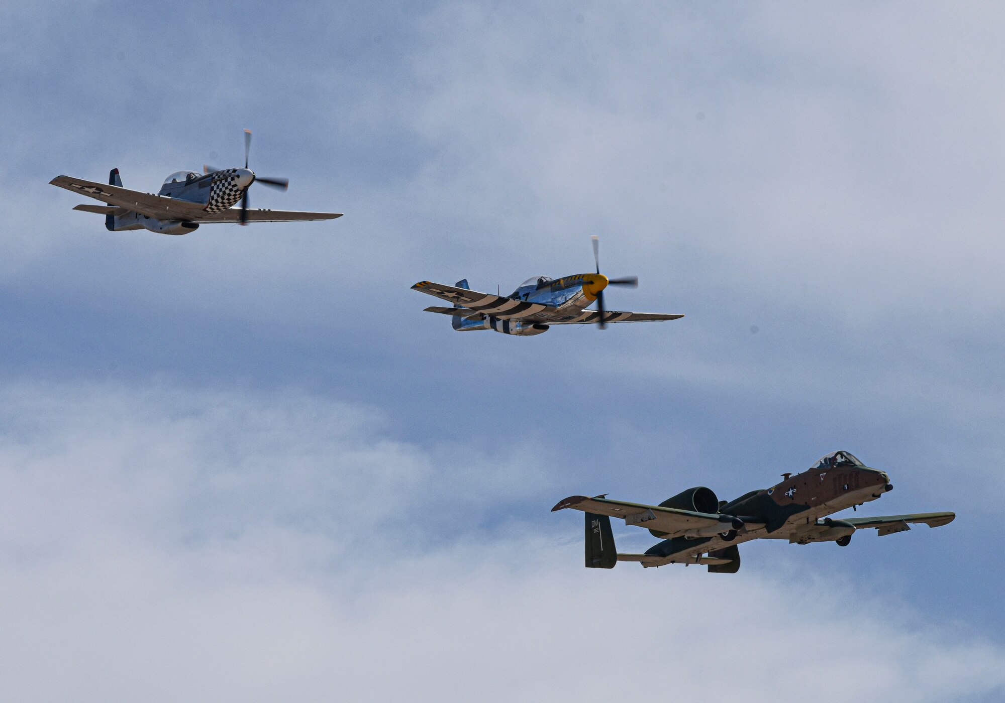 Two P-51 Mustangs and an A-10 flying next to each other.