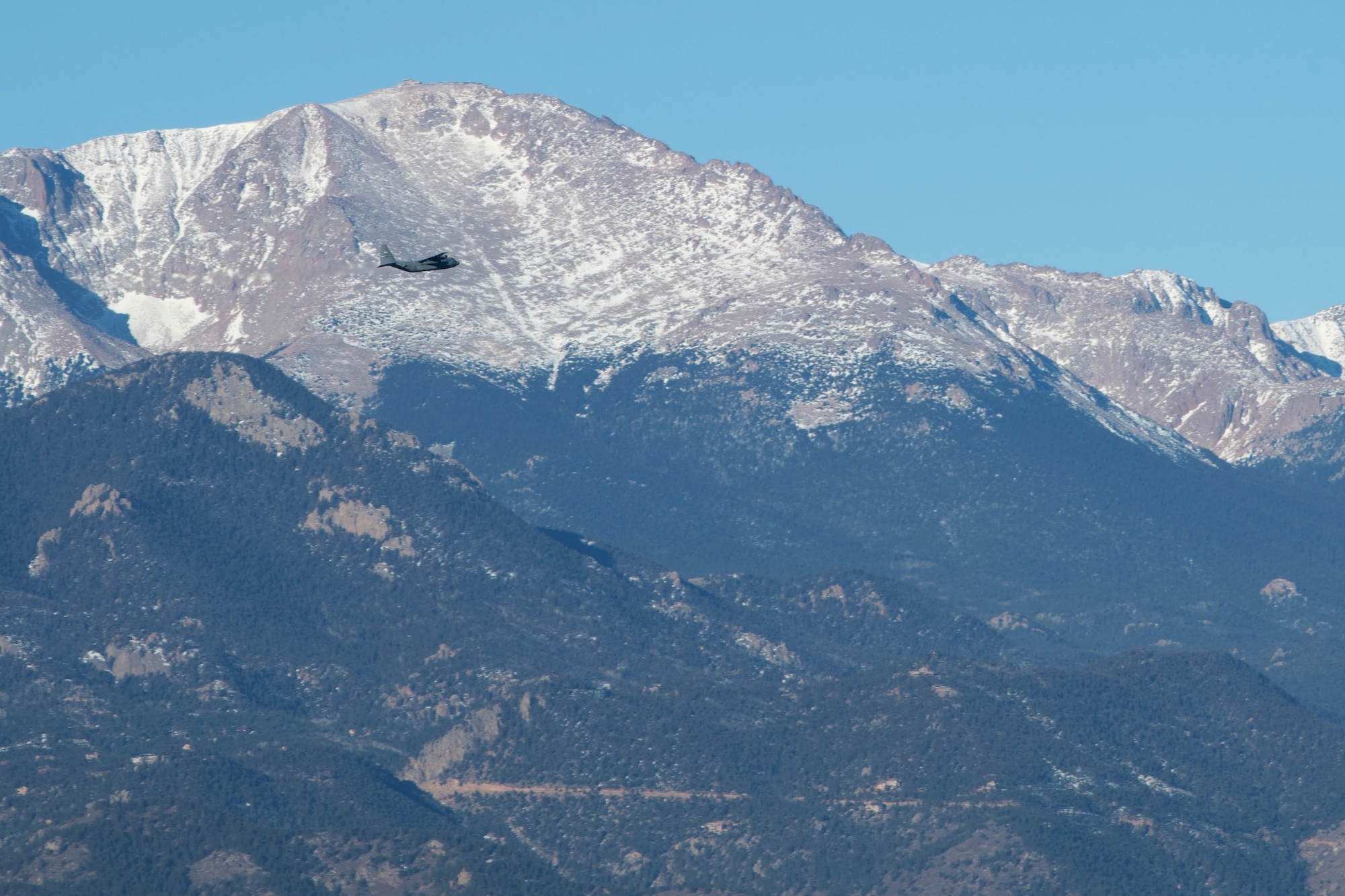 Pikes Peak serves as a backdrop to a 302nd Airlift Wing C-130 aircraft as it departs to an undisclosured location Feb. 5, 2021, Peterson Air Force Base, Colorado.