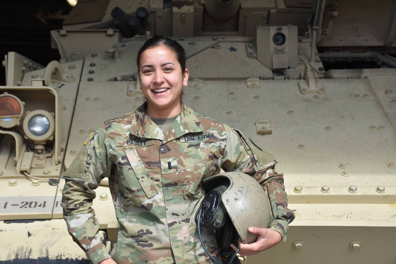 An Army infantry soldier poses in front of a Bradley Fighting Vehicle.