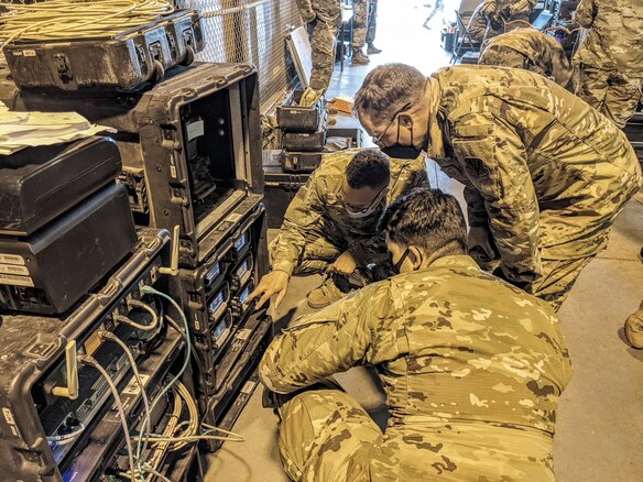 Military members work on communication equipment.