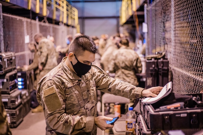 Military member in uniform tests communications equipment.