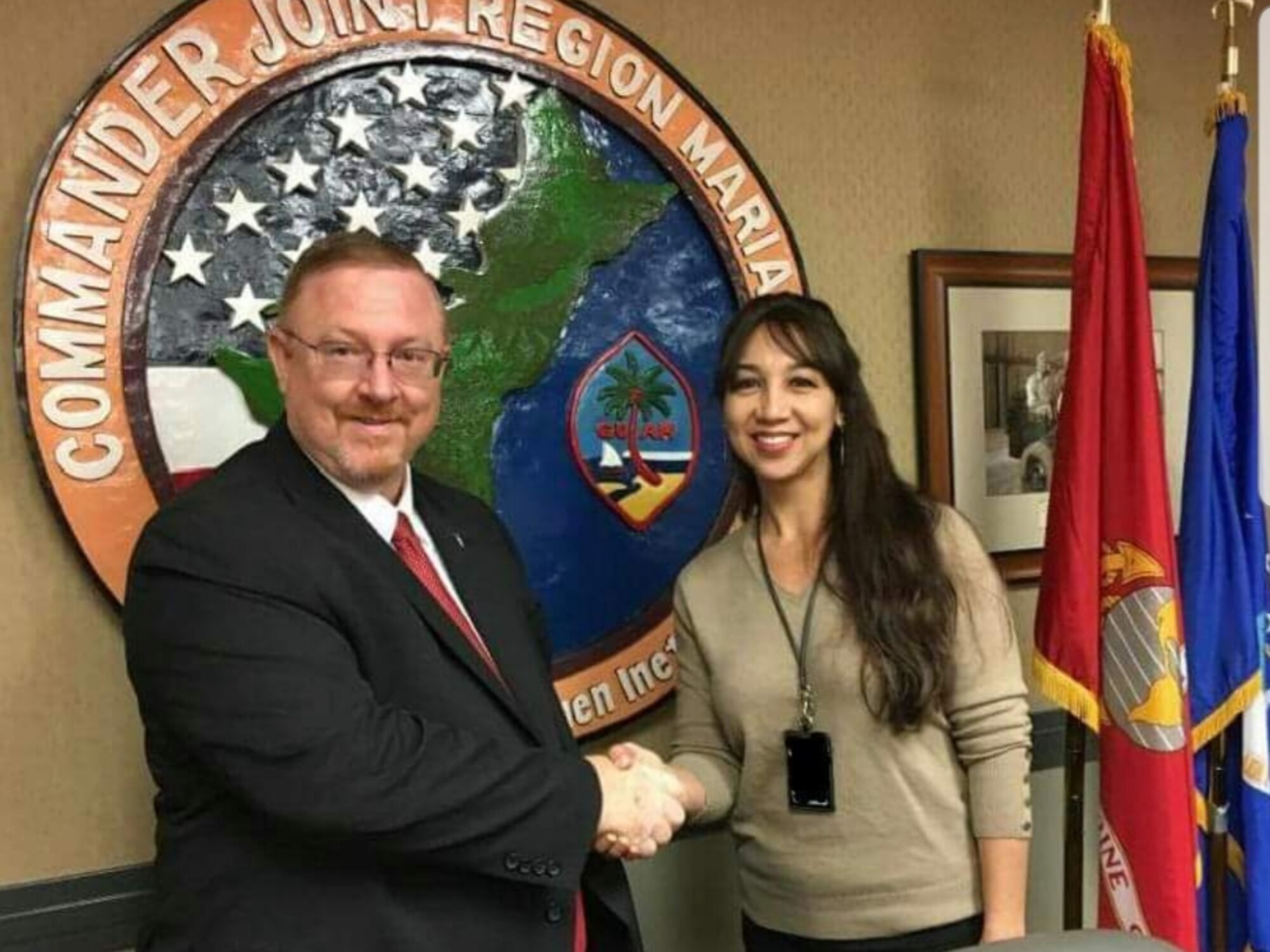 Terry Edwards, former U.S. Air Force Installation and Mission Support Center director, coins Judith Sanchez, 36th Wing program analyst, for her work on the implementation of Joint Region Marianas at the JRM headquarters in Piti, Guam, Apr. 10, 2017. JRM was the merging of U.S. Navy and Air Force forces on Guam, as directed by the U.S. president in 2005.  (Photo courtesy of Judith Sanchez)