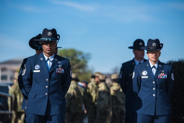 Training instructors stand at parade rest.