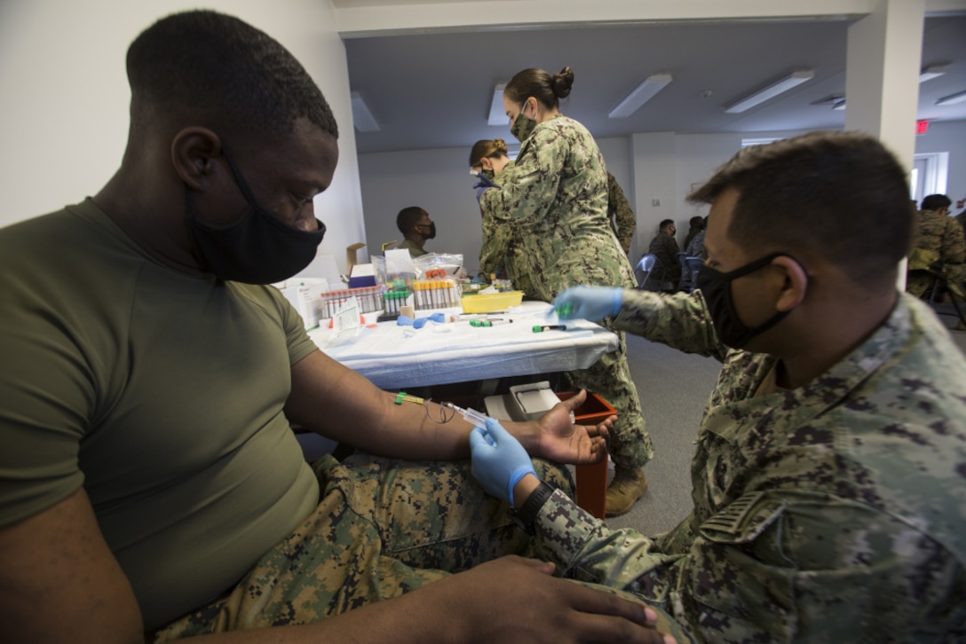 U.S. Navy Hospital Corpsman 1st Class Ernesto Santa Ana, with the Naval Medical Research Center, collects blood samples from a Marine participant with the COVID-19 Health Action Response for Marines (CHARM) study on Camp Johnson, N.C., Mar. 3, 2021.